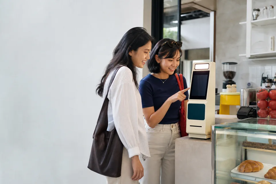 Dua pengunjung mencoba Boothworks Receipt di dekat kasir cafe